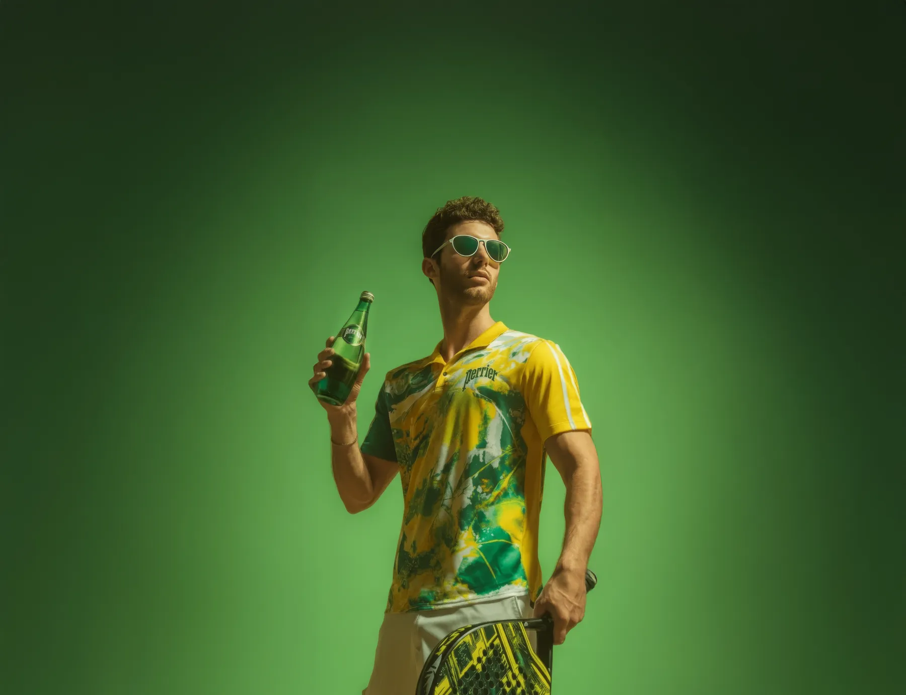 A player in the Perrier × Padel kit holding a bottle and paddle against a green studio backdrop